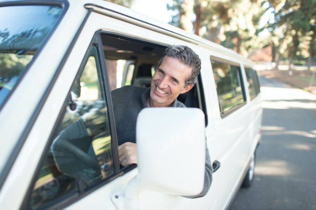 Homem feliz em um van com o braço fora da janela